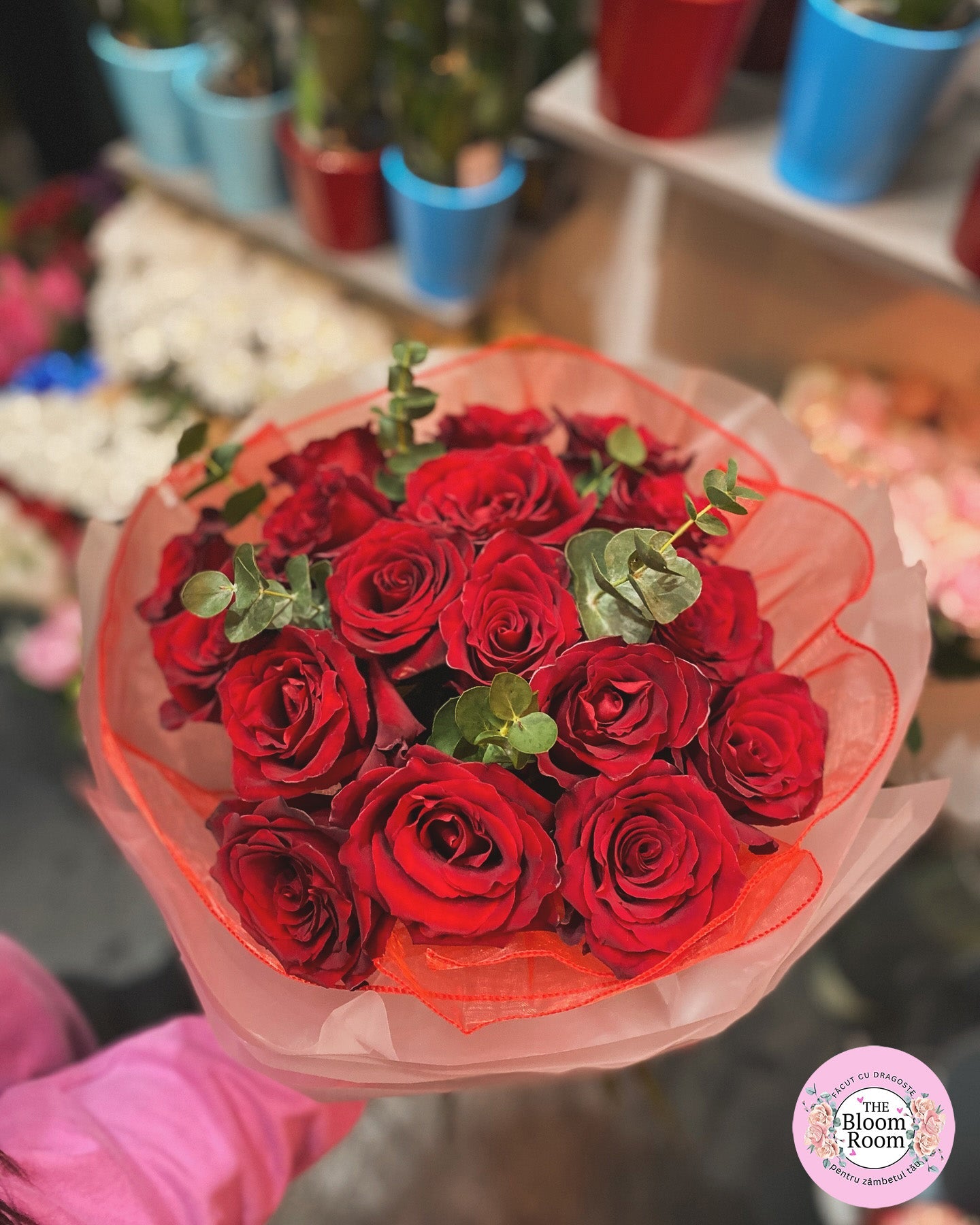 Buchet clasic cu trandafiri roșii și verdeață, simbol al iubirii și pasiunii.